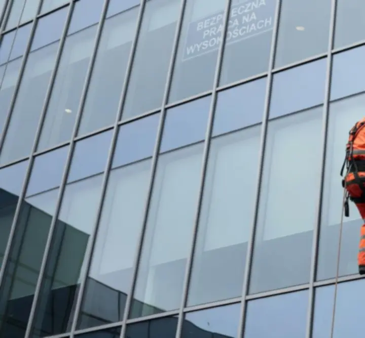 Technik alpinista myjący okna na wysokości